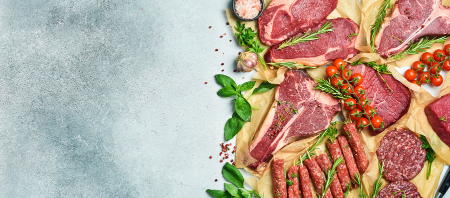 Raw T-bone, rump and sirloin steaks with burgers and sausages on butcher's paper