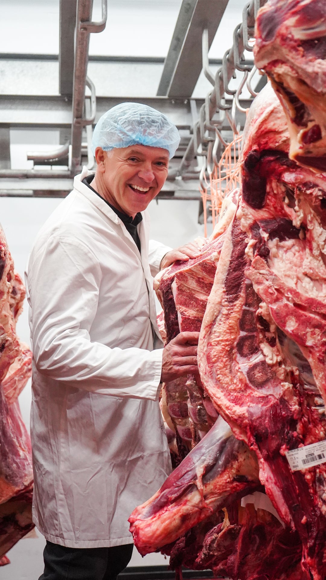 One of our butchers in the cold room beside sides of British beef
