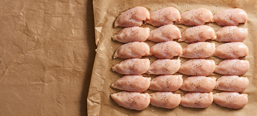 Raw seasoned chicken breast fillets laid out on butcher's paper