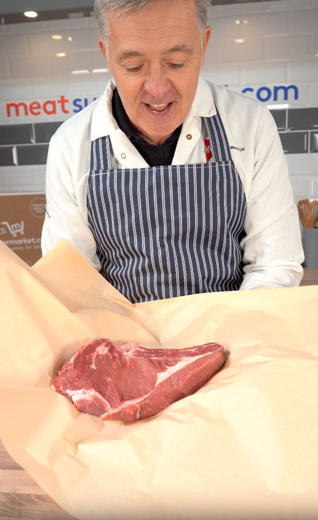 Our butcher unwrapping a bone-in cowboy steak at the counter