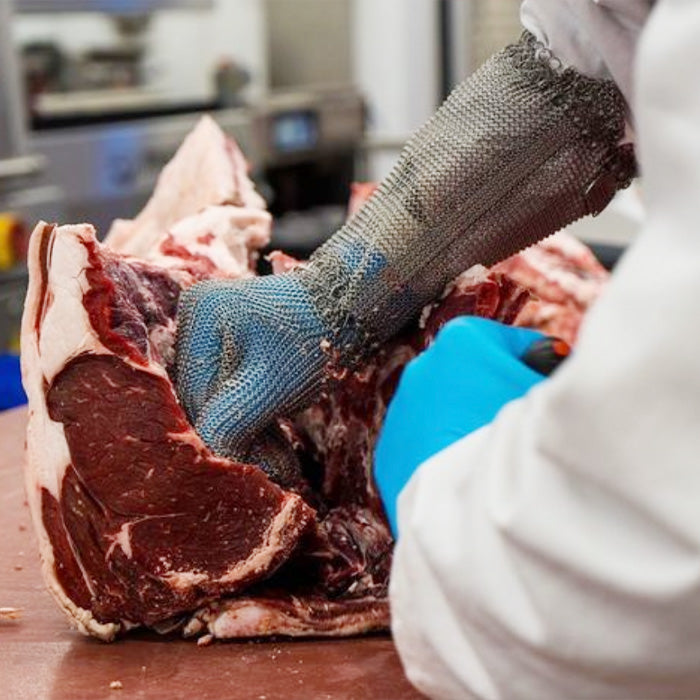 Butcher in a chainmail glove cutting beef by hand – local butcher quality from our online butcher